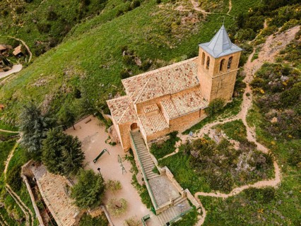 Close-up of a small stone church on a green hill surrounded by paths and trees, aerial view, Las