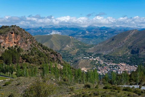Panoramic landscape with mountains, a valley and a village, surrounded by greenery and under a