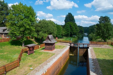 Lock with neighbouring river, surrounded by trees and blue sky with clouds, Mikaszówka lock, Kanal