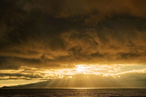 Dramatic sunset with sun rays breaking through the clouds over the sea, Criação Velha, Pico Island,