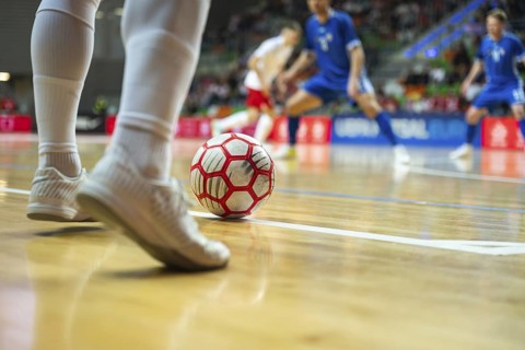 Detail of futsal ball and players legs