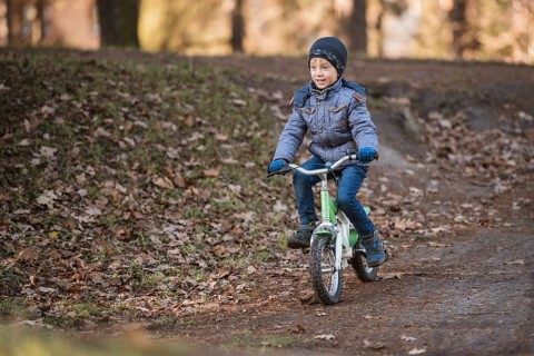 Six years old boy rides bicycle from the hill in the park