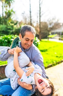 Grandfather and grandson enjoying a playful moment in the park, tickling and laughing together