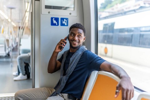 Smart african businessman sitting on the metro talking by mobile next tot he window