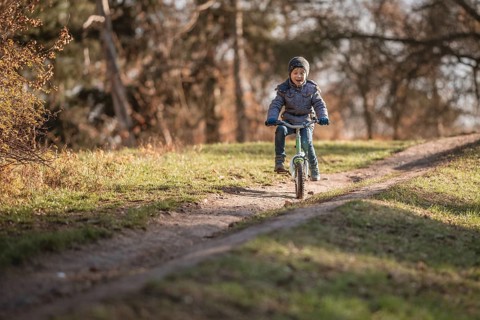 Six years old boy rides bicycle from the hill in the park