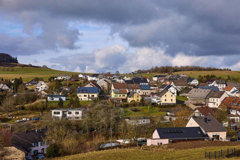 General view, hilly landscape with village, residential buildings, forest, meadows, blue sky,