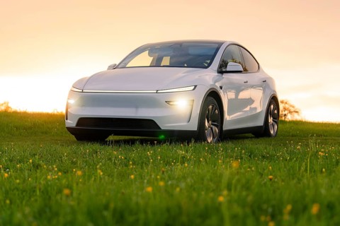 A white car stands on a green meadow in the light of the setting sun, Tesla New Model Y, Germany