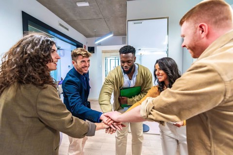 Diverse colleagues joining hands, demonstrating unity, collaboration, and successful teamwork in a