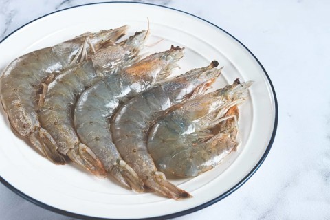Fresh raw white-footed shrimp, tiger prawns vannamei, on a white plate
