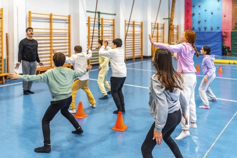 Students practicing gymnastics exercises under the guidance of their teacher in a vibrant school