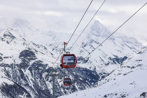 Red cable car cabins take skiers from Zinal to the Sorebois summit station, Val d'Anniviers, Valais