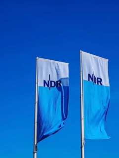 Two flags with lettering NDR, Norddeutscher Rundfunk, flagpoles, colours blue white, light wind,