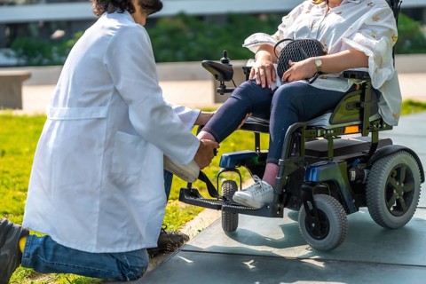 Doctor adjusting the footrest of a patient sitting in an electric wheelchair, providing