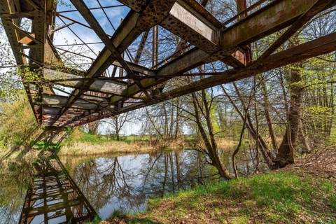 Lost place, disused rusty railway bridge in the forest reflected in the Finow Canal, Liebenwalde,