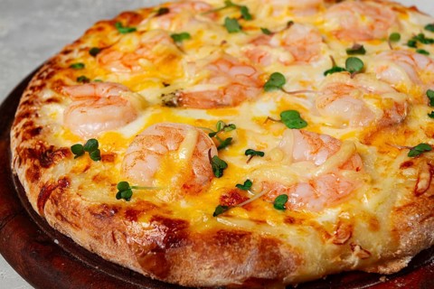 Four cheese pizza with shrimp and fresh microgreens, served on a wooden board, homemade, no people