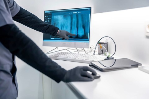 Dentist pointing at a dental x ray on a computer screen, showcasing modern dental diagnostics in a