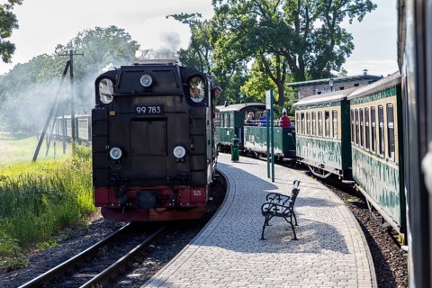 A steam locomotive pulling wagons, shot from behind on a sunny platform, Rügen, Rasender Roland