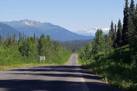 Narrow, traffic-free road leads as endless grades through rugged mountain landscape, forest and