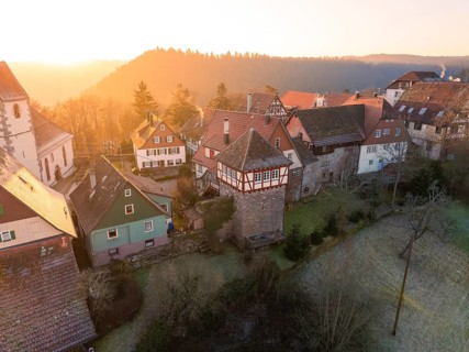 A village with half-timbered houses and a historic tower in wintry surroundings at sunset,