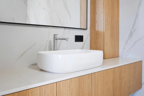 A beautifully designed bathroom features a sleek, white oval sink atop a minimalist countertop. The