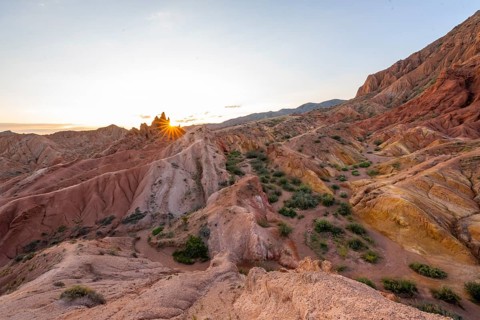 Erosion landscape of red and yellow sandstone, rock formations at sunrise with sun star, Skazka
