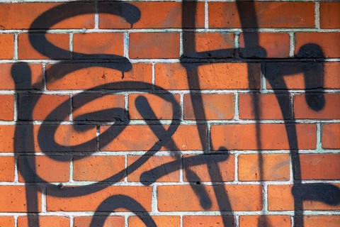 Close-up of a brick wall with black graffiti, Copenhagen, Denmark