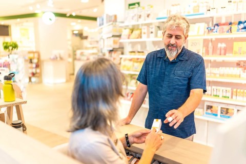 Rear view of a female mature pharmacist assisting a customer in the counter