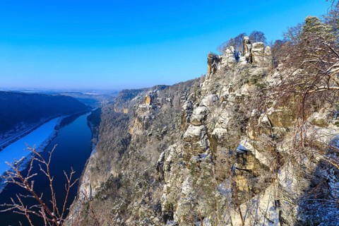 Kanapee viewpoint at the Bastei into the snow-covered Elbe valley with sandstone cliffs such as the