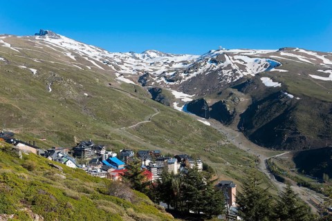 A mountain village with colourful houses in a snowy mountain landscape under a clear sky, left Pico