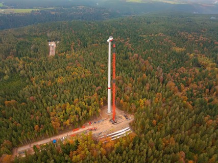 The construction of a wind turbine in the middle of an extensive autumn forest, wind farm