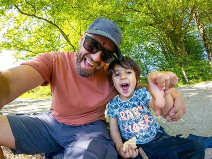 Father and son taking a selfie, enjoying a sunny day in the mountains, having a snack and making