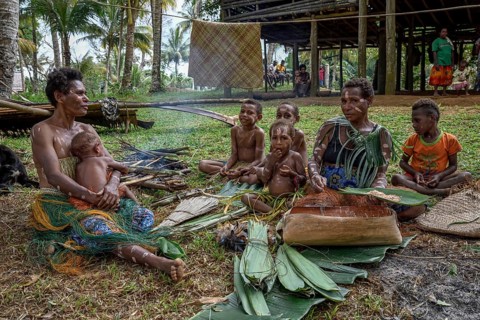 Local woman preparing banana leaves with roasted marrow of the Sago palm, village Pangoa, island