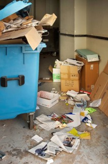 Overfilled blue paper bin, paper waste on the floor