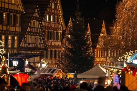 Christmas market with illuminated half-timbered houses and crowds of people in a festive