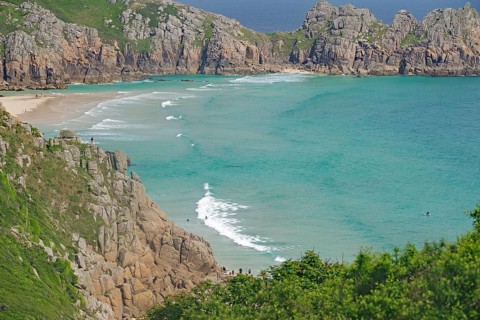 Türkisfarbenes Meer zwischen steilen Klippen und grüner Landschaft, Porthcurno, St Levan, Cornwall,