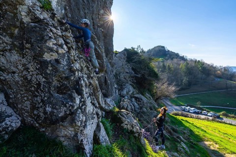 Two female rock climbers scaling a cliff face, enjoying a sunny day in a picturesque natural