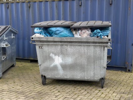 Full rubbish container not emptied by refuse collection Waste bin overflowing with rubbish bags and