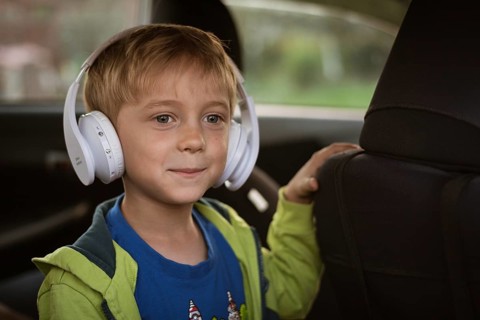 Six years old boy with headphones singing in the car