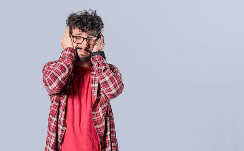 Man suffering covering ears isolated. Unhappy guy covering his ears isolated