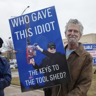 Troy, Michigan USA - 29 March 2025 - People gathered in the rain outside the Tesla Showroom at the