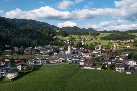 Drone shot, view of the village with parish church, Kössen, Leukental, Tyrol, Austria