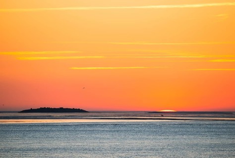 Picturesque, golden, breathtakingly beautiful sunset over the sea, island Langlütjen II far away on