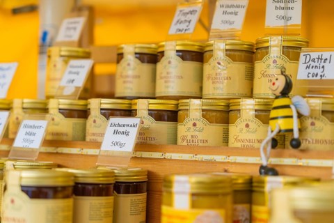 Shelves with different types of honey and a small bee figurine on a market stall, Sindelfingen,