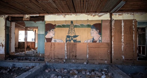 Destroyed abandoned classroom of the old school, wall painting with Soviet miners, ghost town,