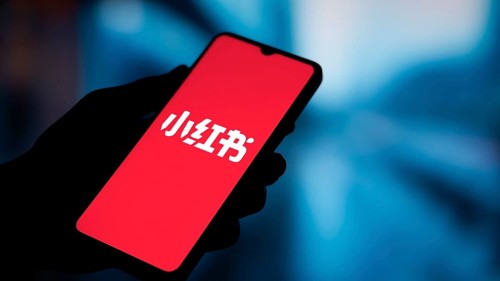 RedNote (Xiaohongshu) logo is displayed on smartphone