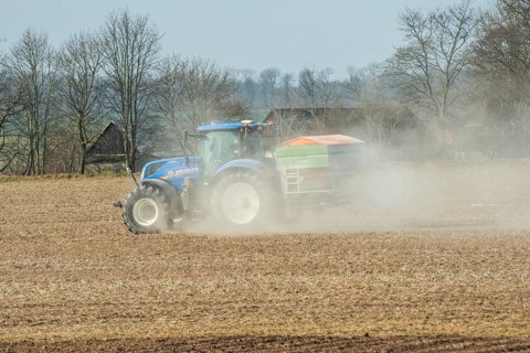 Spring farming, spreading fertilizer with tractor on field in Ystad municipality, Skåne county,
