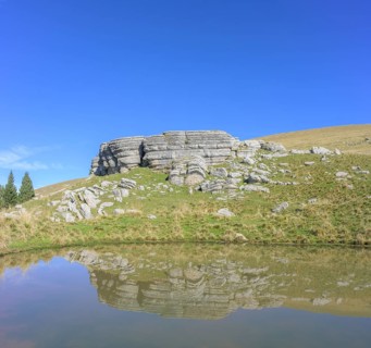 Surface karst rock formations are reflected in a pond, circular hike Monte Fior, Foza, province of