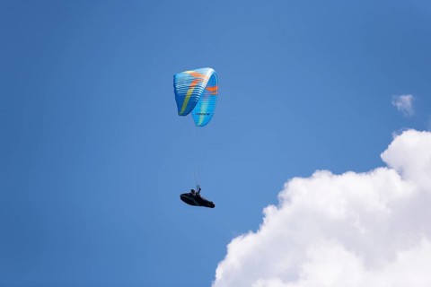 Paraglider soaring through an open and cloudy sky, Bavaria, Germany