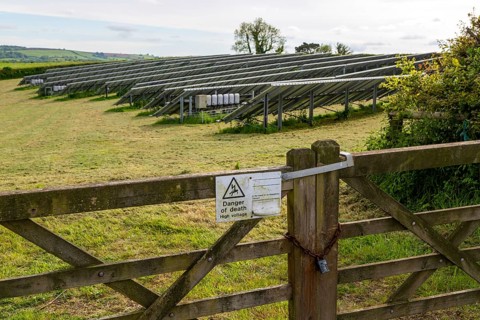 Danger of death sign on gate to field of solar panels, Dartington Hall estate, south Devon,