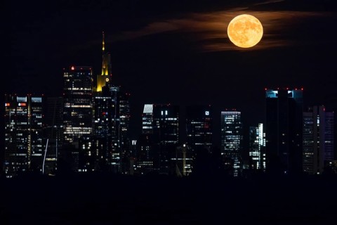 The full moon, known as the strawberry moon in June, passes over the Frankfurt banking skyline,